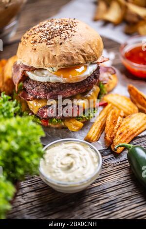 Hamburger doppio di manzo con pancetta con formaggio e lattuga, uova, patatine e maionese o condimento Foto Stock