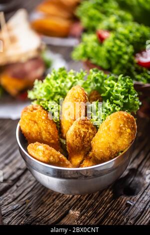 Bocconcini di pollo con insalata in una ciotola di metallo su una superficie rustica di legno Foto Stock