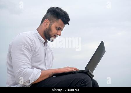 Giovane uomo che lavora sul computer portatile Foto Stock