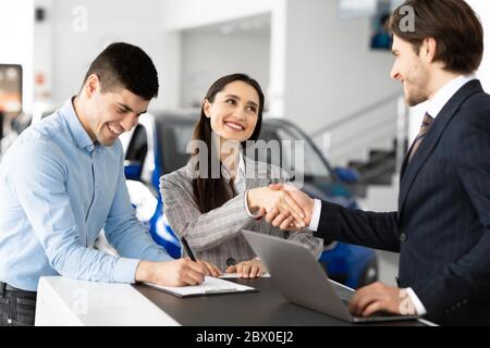 Coniugi Acquisto di auto e Handshaking con Venditore uomo Foto Stock