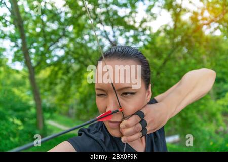 tiro con l'arco, giovane donna con una freccia in un arco focalizzata sul colpire un bersaglio Foto Stock
