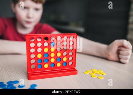Il bambino sta pensando alla strategia in un gioco da tavolo 'Pick Four in a row' Foto Stock