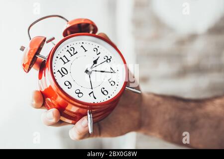 Primo piano di un uomo caucasico che regola l'ora di un orologio - non si può dormire troppo o perdere importanti eventi e cose Foto Stock
