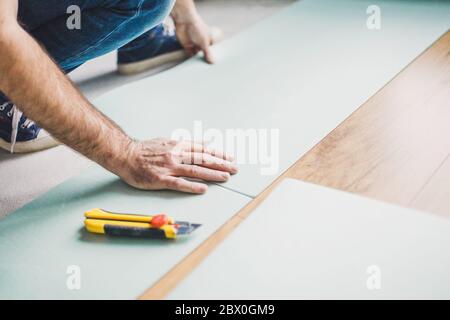 Un lavoratore installa un pavimento laminato durante il lavoro di finitura Foto Stock