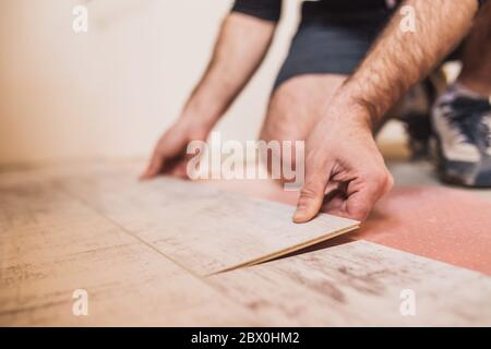 Un lavoratore bussa a mano su un laminato che collega i pannelli con un clic di blocco Foto Stock