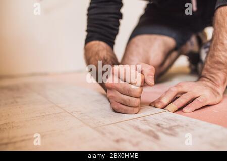 Un lavoratore bussa a mano su un laminato che collega i pannelli con un clic di blocco Foto Stock