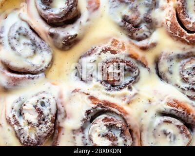 panini alla cannella appena sfornati, avvolgiati con salsa dolce alla crema da vicino Foto Stock