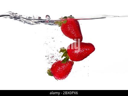 Closeup di fragole fresche e salutari in acqua limpida isolato su sfondo bianco. Lavare la frutta Foto Stock