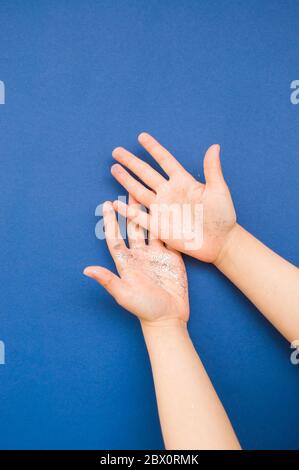 Mani per bambini con glitter e confetti di colore blu e argento su sfondo blu classico. Foto Stock