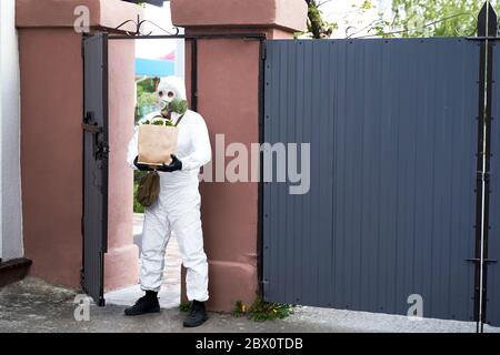 un uomo in abbigliamento protettivo e una maschera a gas portato cibo Foto Stock