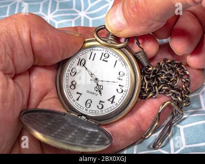 Chiudi POV delle mani di un uomo che fissa il tempo su un orologio tascabile in ottone al quarzo con catena attaccata. Foto Stock