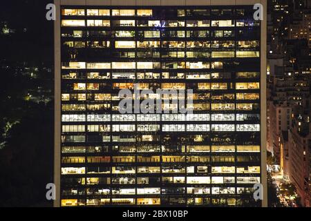 Vista mozzafiato di alcuni uffici illuminati in un edificio situato nel centro finanziario di Manhattan, New York City, USA. Foto Stock