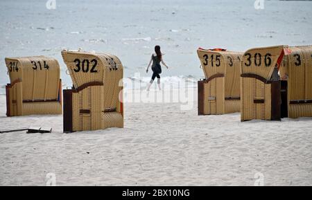 04 giugno 2020, Schleswig-Holstein, Eckernförde: Una donna cammina lungo la spiaggia del Mar Baltico davanti a sedie da spiaggia chiuse. Foto: Carsten Rehder/dpa Foto Stock