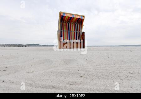 04 giugno 2020, Schleswig-Holstein, Eckernförde: Una sedia da spiaggia chiusa in vimini si erge sulla spiaggia del Mar Baltico quando il cielo è nuvoloso. Foto: Carsten Rehder/dpa Foto Stock