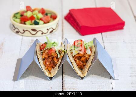 Due tacos vegan trainati con jackfruit realizzati con tortillas di mais morbido in un supporto per tortilla. Foto Stock