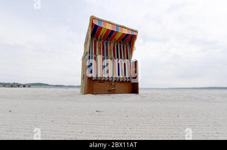 04 giugno 2020, Schleswig-Holstein, Eckernförde: Una sedia da spiaggia chiusa in vimini si erge sulla spiaggia del Mar Baltico quando il cielo è nuvoloso. Foto: Carsten Rehder/dpa Foto Stock