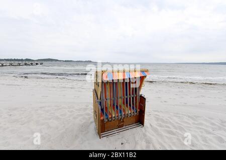 04 giugno 2020, Schleswig-Holstein, Eckernförde: Una sedia da spiaggia chiusa in vimini si erge sulla spiaggia del Mar Baltico quando il cielo è nuvoloso. Foto: Carsten Rehder/dpa Foto Stock