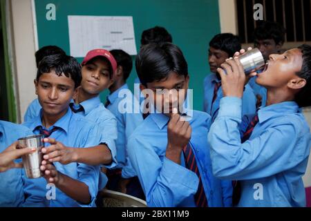 Gli studenti della Sujata Technical School prendono a turno per bere integratori alimentari forniti dagli insegnanti dopo un briefing giornaliero dopo le lezioni al complesso della Sujata Academy nel villaggio di Dungeshwari a Bihar, in India. Costruito come aiuto per l'istruzione dei bambini nelle zone rurali, il complesso gratuito di scuola e dormitorio è gestito dalla Join Together Society, un'organizzazione di soccorso con sede nella Corea del Sud. Secondo le statistiche dell'UNESCO, il numero di bambini fuori scuola in India nel 2013 è stato di oltre 2 milioni (maschi) e quasi 1 milioni (femmine). Il Bihar è uno degli stati più poveri dell'India. Foto Stock