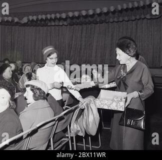 Anni '60, storica, in un pranzo di natale di vecchi popoli all'interno del municipio, una vecchia signora felice tirando un cracker di Natale con la principessa Alice in una visita reale, Lewisham, Londra del sud, Inghilterra, Regno Unito. Nata nel 1885 al Castello di Windsor, la principessa Alice di Battenberg era la madre del principe Filippo, marito della regina Elisabetta II Foto Stock