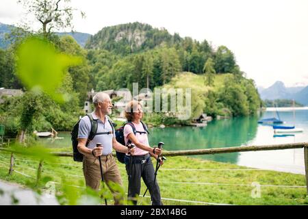 Coppia anziana di pensionati con nordic walking pali escursionistici in natura, parlando. Foto Stock