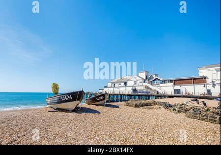 Piccole barche da pesca spiaggiate sulla ghiaia con pentole di aragosta presso il molo di Bognor Regis, una cittadina balneare nel Sussex occidentale, costa meridionale dell'Inghilterra Foto Stock