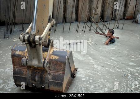 Lavoratori edili immersi in acqua che lavorano con un operatore di retroescavatore su impianti di drenaggio. Thailandia Sud-est asiatico Foto Stock