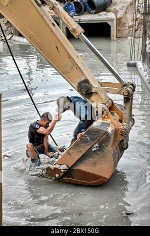 Lavoratori edili in acqua che lavorano con un operatore di retroescavatore su impianti di drenaggio. Thailandia Sud-est asiatico Foto Stock