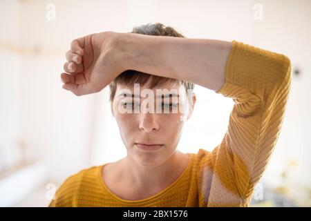 Vista frontale della giovane donna triste in piedi all'interno a casa, primo piano. Foto Stock