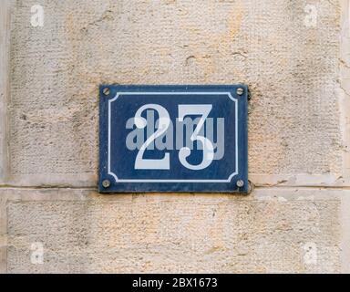 Casa numero 23 Bianco su blu su un vecchio muro di pietra calcarea di metallo di una casa franca autentica Foto Stock
