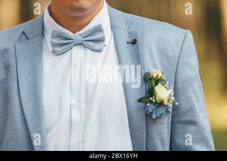 Gallo in una giacca blu con una cravatta blu. Sulla giacca è un boutonniere di rose Foto Stock