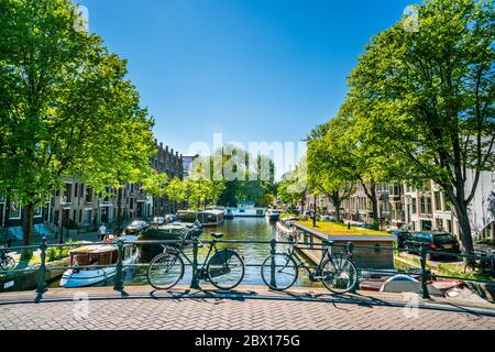 Amsterdam, 7 maggio 2018 - Vista sul canale Achtergracht con barche e biciclette in estate Foto Stock