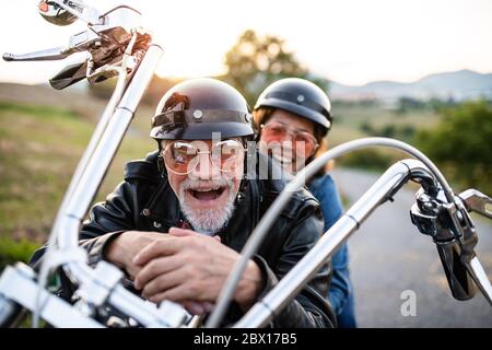 Una coppia anziana allegra con moto in campagna. Foto Stock