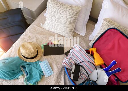 Accessori per vacanze estive preparati sul letto e maschera per viaggi vacanze in stagione di coronavirus in camera da letto. Vista dall'alto Foto Stock