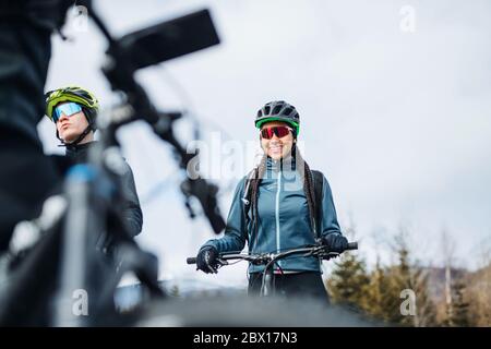 Gruppo di mountain bike in piedi su strada all'aperto in inverno, parlando. Foto Stock