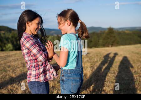 Due bambini della scuola camminano sul campo in natura, giocando. Foto Stock