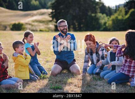 Gruppo di bambini con insegnante in gita in campo in natura, canti. Foto Stock