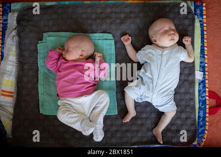 I gemelli del bambino e del ragazzo del neonato dormono su un tappeto. Foto di Sam Mellish Foto Stock