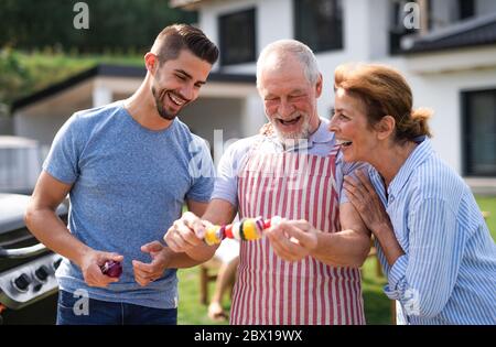 Ritratto di famiglia multigeneration all'aperto su barbecue giardino, grigliatura. Foto Stock