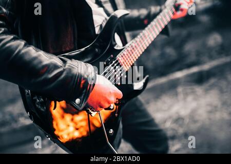 Chitarrista che suona hard rock su una chitarra elettrica nera al buio - riflesso del fuoco Foto Stock