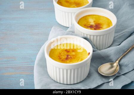 Crema catalana, dessert spagnolo in tre ramekin su tavolo blu, spazio copia Foto Stock