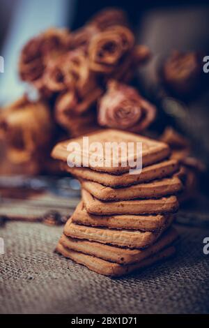 Biscotti impilati su tovagliolo marrone. Immagine simbolica. Un pacchetto di biscotti per uno spuntino gustoso. Dolce dessert. Rustico sfondo in legno. Selettivo Foto Stock