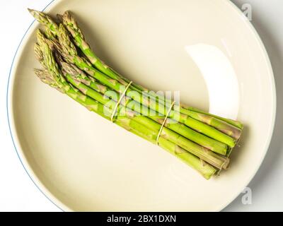 Un mazzo di asparagi in una ciotola su fondo bianco Foto Stock