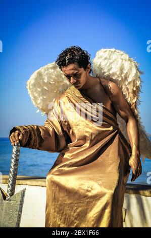 Puerto Vallarta, Messico - Gennaio 2012: Bell'uomo si pone come una statua di angelo vivente, vestito in costume d'oro con ali di piuma. Foto Stock