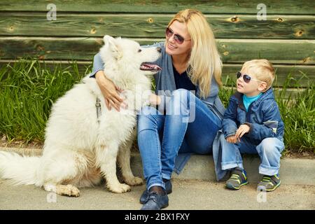 ritratto esterno madre, figlio e cane. bambino e mamma che cammina samoyed laika. Foto Stock