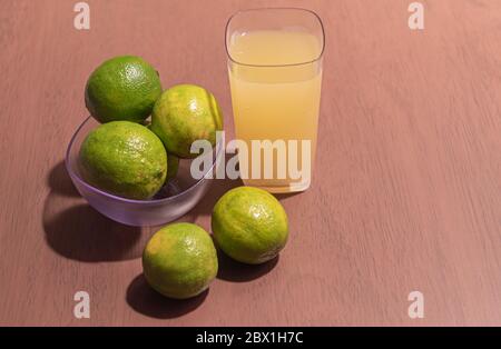 Limoni verdi e un bicchiere di succo di limone tahiti (Citrus latifolia tanaka). La sua pelle è sottile e liscia, la polpa ha una grande quantità di succo, intenso f Foto Stock