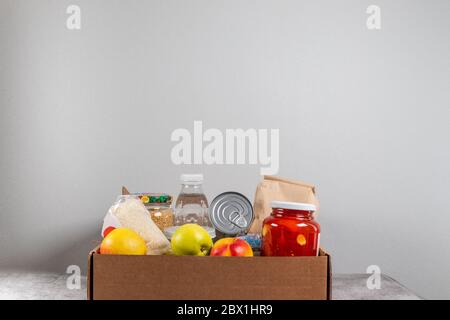 Aprire le forniture alimentari in scatola di donazione per le persone in isolamento a su tavola grigia Foto Stock