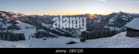 Panorama, vista sulla Valle di Brixen con i primi raggi di sole, alba dietro una catena montuosa in inverno, Hochbrixen, Brixen im Thale, Tirolo Foto Stock