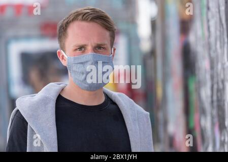 Giovane uomo che indossa una maschera protettiva per la bocca, Corona Crisis, Monaco, Baviera, alta Baviera, Germania Foto Stock