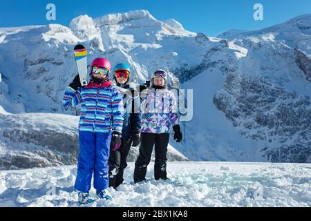 Ragazza con attrezzatura da sci su spalla in un gruppo di amici sopra la vetta di montagna sullo sfondo Foto Stock