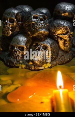 teschi con candela che brucia su sfondo di legno nel buio Foto Stock